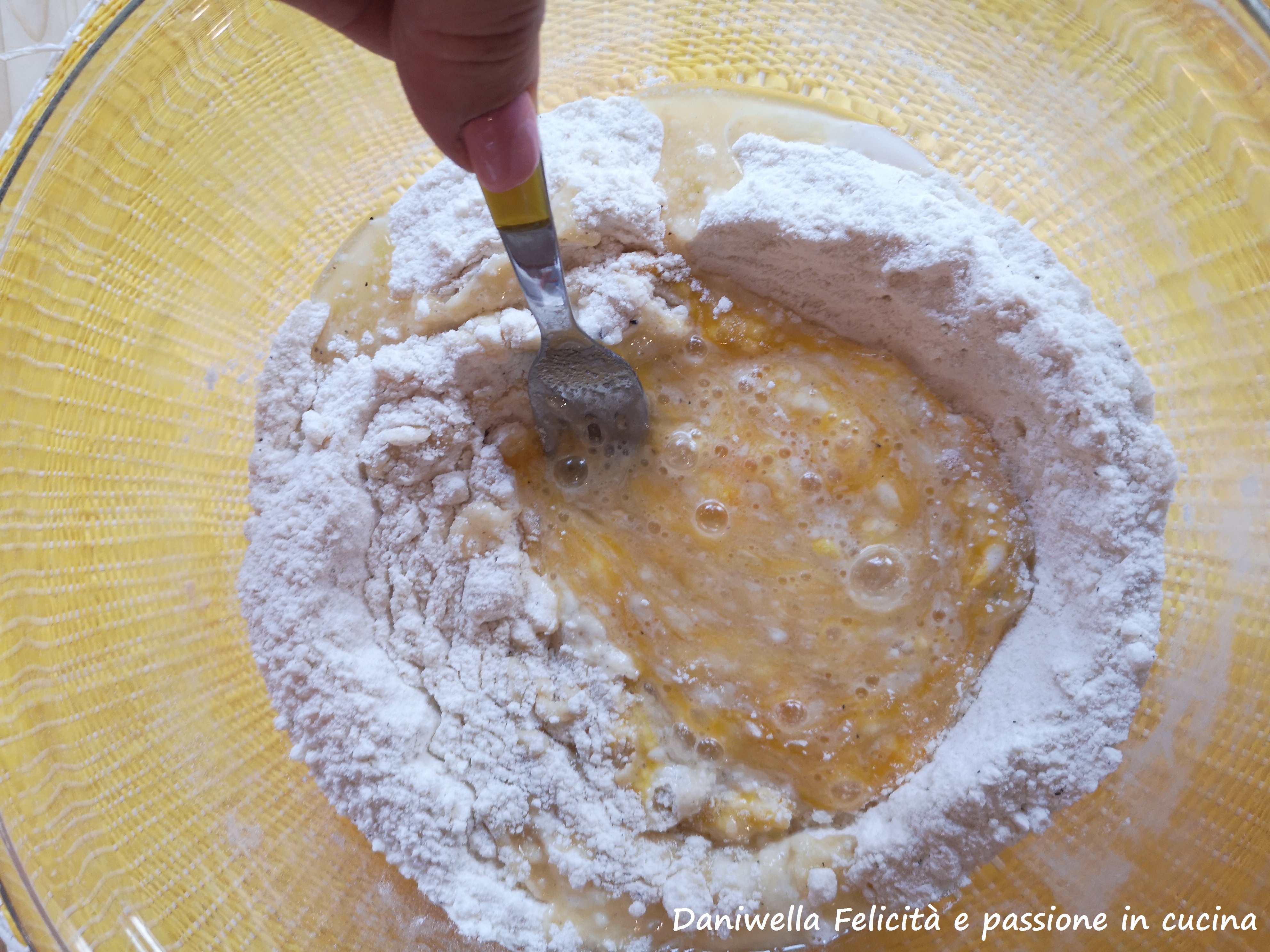 Fate un cratere al centro e versate l’uovo, l’olio e il vino. Partendo dal centro sbattete gli ingredienti liquidi e pian piano incorporate la farina.